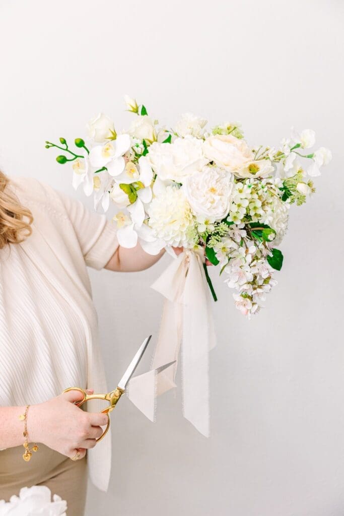 florist using sharp scissors to cut ribbon on real touch flower wedding bouquet